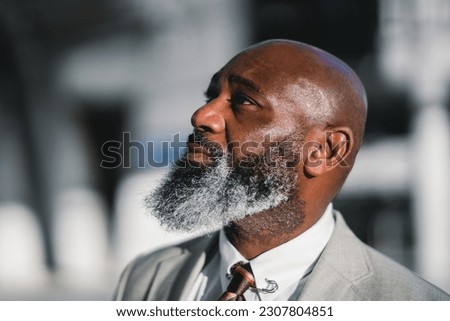 A close-up portrait of the profile of a charming black man with a long greying beard, dressed in a grey suit jacket, captured with selective focus, highlighting his distinguished features Royalty-Free Stock Photo #2307804851