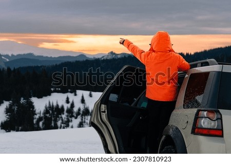Man in car pointing to mountain at sunset