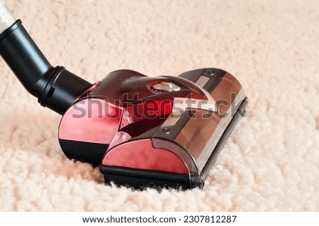 Home cleaning concept. Close up of the head of a modern hoover being used while vacuuming a woollen furry carpet. Royalty-Free Stock Photo #2307812287