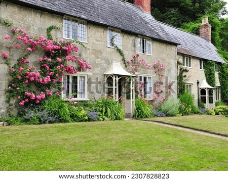 Exterior view and garden of a beautiful old cottages houses on a street in an English village Royalty-Free Stock Photo #2307828823
