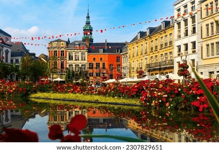 Picturesque summer view of flowering central Grand Place square in Mons overlooking baroque belfry of Roman Catholic Church of St. Elizabeth towering over colorful residential townhouses, Belgium Royalty-Free Stock Photo #2307829651