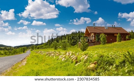 A wooden cottage with a green lawn. Cottage with panoramic windows. Glazing of cottages. Large windows in the house. Royalty-Free Stock Photo #2307834585