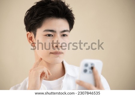 Young handsome man with a serious look on his face holding his phone Up