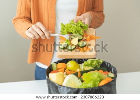Compost from leftover food, asian young housekeeper woman hand holding cutting board use fork scraping waste, rotten vegetable throwing away into garbage, trash or bin. Environmentally responsible. Royalty-Free Stock Photo #2307886223