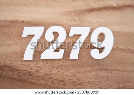 White number 7279 on a brown and light brown wooden background.