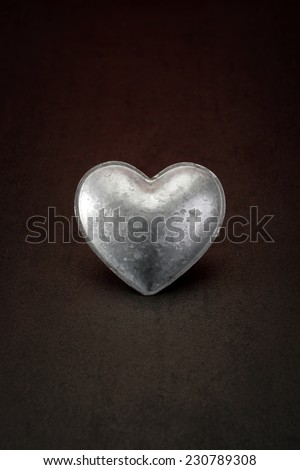 metal heart on a stone background symbolizing cold-hearted people for valentine's day