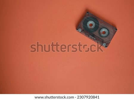 Audio cassette in the corner on brown background, top view.