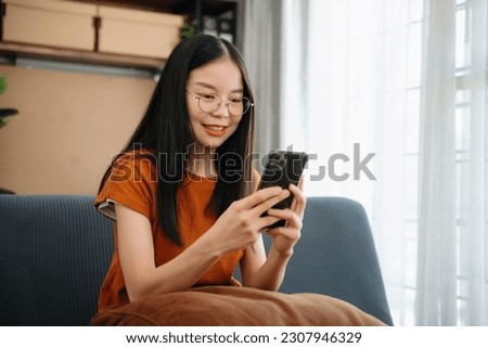 Asian young woman using the smartphone and tablet on the sofa at home
