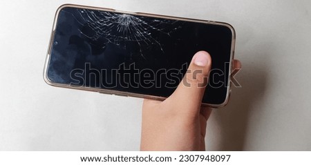 A mobile phone with a cracked screen due to a fall