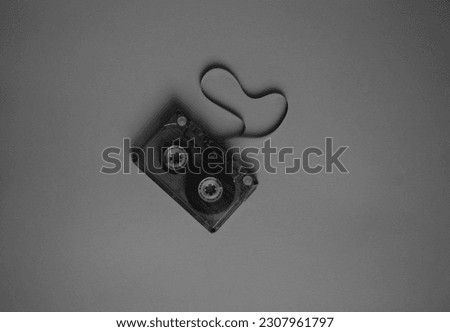 Audio cassette with stretched tape in black and white color, top view.