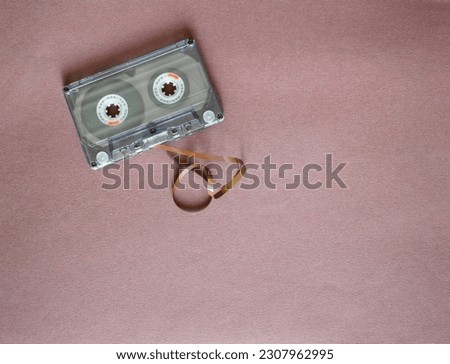 Audio cassette with tangled tape on a purple background, top view.