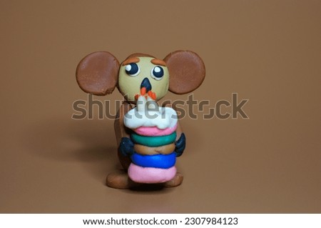 Cheburashka with a toy cake on a brown background. Children's toys. A cartoon character.