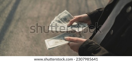 person standing outside and counting dollar cash banknotes Royalty-Free Stock Photo #2307985641