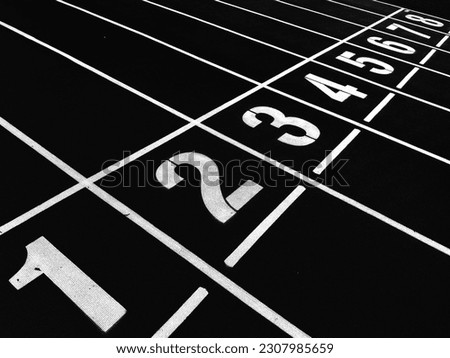 Numbers on red running track. Start and Finish point of a race track in a stadium(Black and white photo)