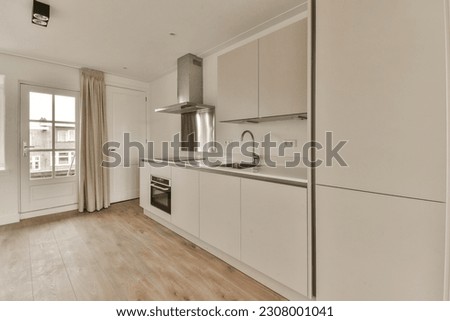 a kitchen with white cabinets and wood flooring in the middle of the room, there is an oven on the right side Royalty-Free Stock Photo #2308001041
