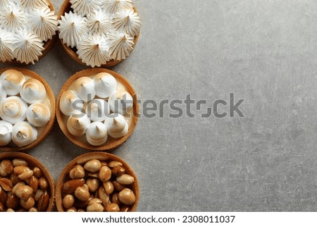 Many different tartlets on light grey table, flat lay with space for text. Tasty dessert