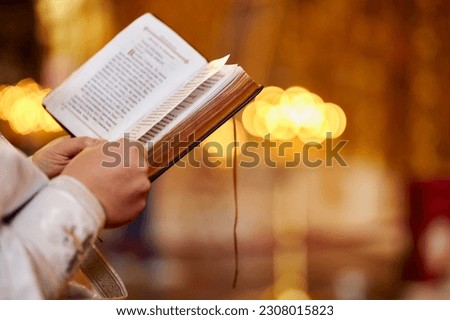 An Orthodox priest holds a Bible in his hands. Close-up of unrecognizable hands of a priest holding a bible in a church. A priest with a Bible. Christianity or Catholicism, faith in God. Church ritual Royalty-Free Stock Photo #2308015823
