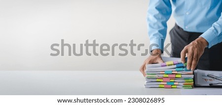 Businessman working on stacks of documents to search for information and check documents on office desk