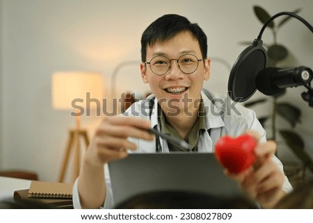 Doctor using microphone and laptop computer to recording audio about medication advise. Healthcare, medicine and blogging concept