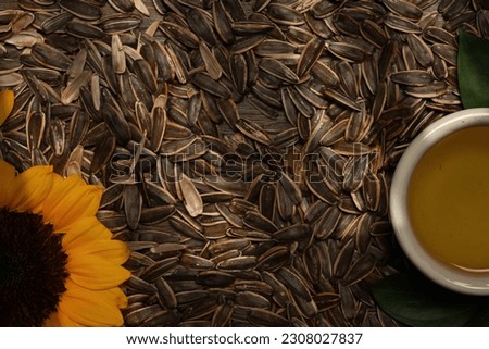 Organic sunflower oil in a small bowl with sunflower seeds and fresh flowers on wooden background