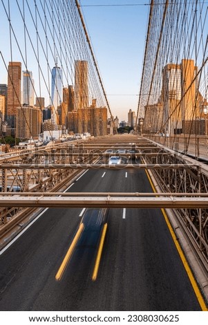 Moving cars on the Brooklyn Bridge in the New York City in the morning dawn.