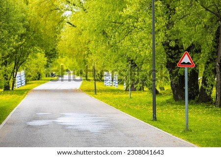 road sign in the park indicating a rough road. uneven road surface. empty road in summer park