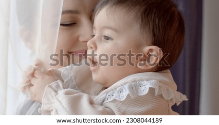 Portrait of a baby in the arms of mother. The mental peace of the child is safe. Maternal attachment of personality in education. Short hair. Royalty-Free Stock Photo #2308044189