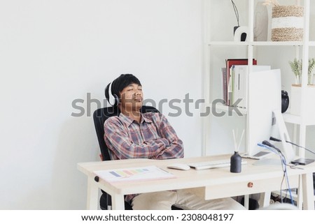 Young asian entrepreneur resting while listen to music with headphones after fulfilling a large number of email orders. Work from home concept.