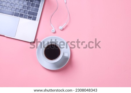 Minimalist feminine office desktop with laptop, cup of coffee and earphones with copy space on pink background. Flat lay, top view, space for text.
