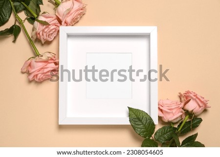 Empty photo frame and beautiful flowers on beige background, flat lay. Space for design