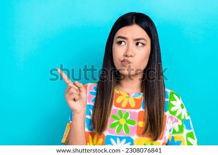 Photo of adorable suspicious lady wear flower print t-shirt looking showing finger empty space isolated blue color background