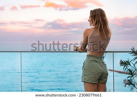 Beautiful young woman standing and looking at the sea and sky Royalty-Free Stock Photo #2308079661