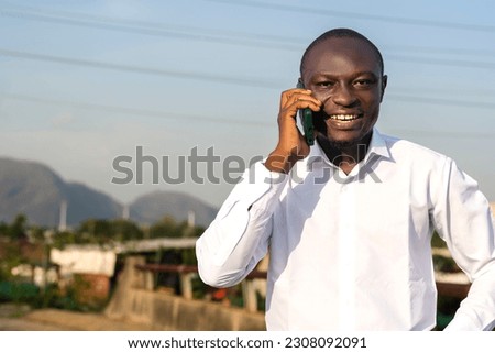 Photo of a black businessman in a white shirt having a phone conversation