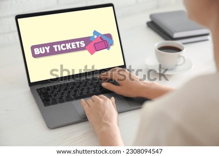 Woman buying tickets online via laptop at table, closeup