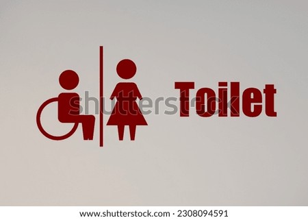 Red public toilet sign on white wall