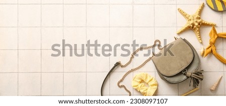 Stylish bag and female accessories on light tile background with space for text