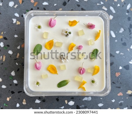 Cheese cake topping with flowers and leaves that can eat in plastic tray on terrazzo table