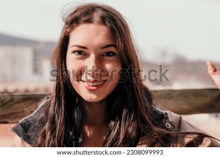 Happy young smiling woman with freckles outdoors portrait. Soft sunny colors. Outdoor close-up portrait of a young brunette woman and looking to the camera, posing against autumn nature background