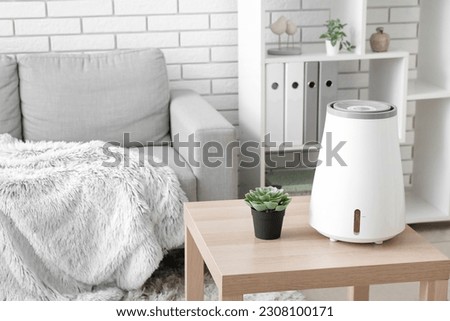 Modern humidifier and houseplant on table in interior of living room Royalty-Free Stock Photo #2308100171
