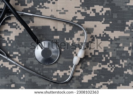 Stethoscope lies on the uniform of a US soldier. The concept of health care, military insurance, state care. Top view. Mixed media