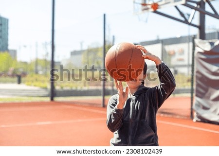 A girl with basketball on court on summer season.
