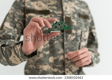 A military man is holding a chip electronic components. microcircuits, green camouflage.