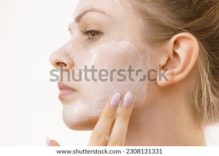 Young woman applying facial cream cosmetic, mask moisturizing to her face. Perfect skin. Beauty, wellness and skincare.