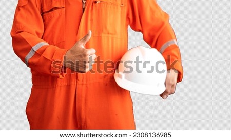 An engineer in orange coverall PPE is thumbing up during holding a white safety helmet, ready to working in unsafe workplace concept. Isolated photo applied with clipping path. Royalty-Free Stock Photo #2308136985