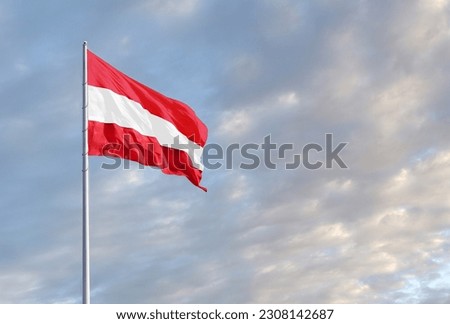 Waving Austrian flag against a blue sky with clouds and empty space for text. Room for text.