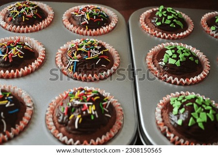 Fresh chocolate cupcakes with icing and colorful decor. Homemade baking.