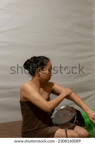 Asian woman in brown towel sitting and applying cream