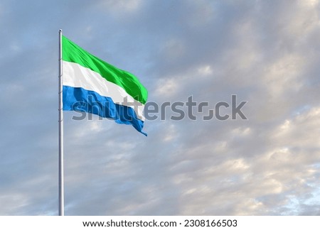 Waving Sierra Leone flag against a blue sky with clouds and empty space for text. Room for text. Royalty-Free Stock Photo #2308166503