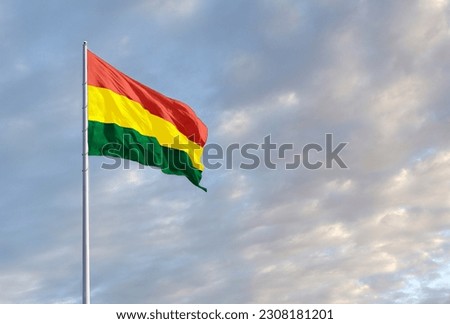 Waving Bolivian flag against a blue sky with clouds and empty space for text. Room for text.