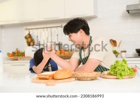 Asian boy showing strong arm , playful with his father in home  Royalty-Free Stock Photo #2308186993